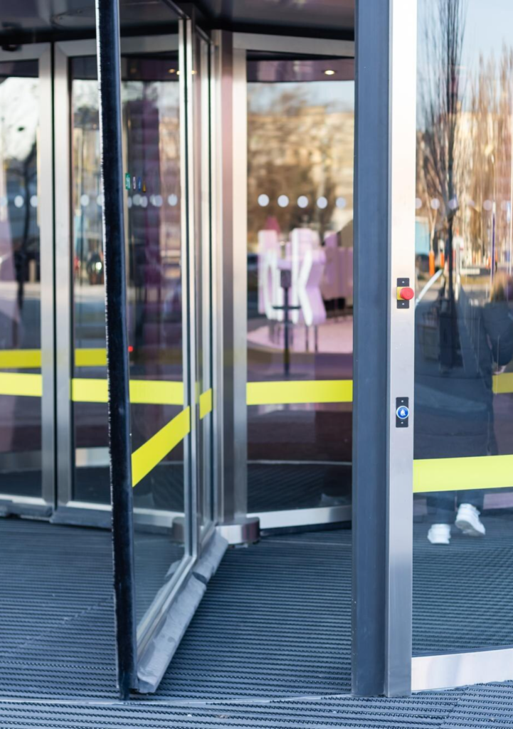 Portes tournantes automatiques en verre installées à l’entrée d’un bâtiment moderne.