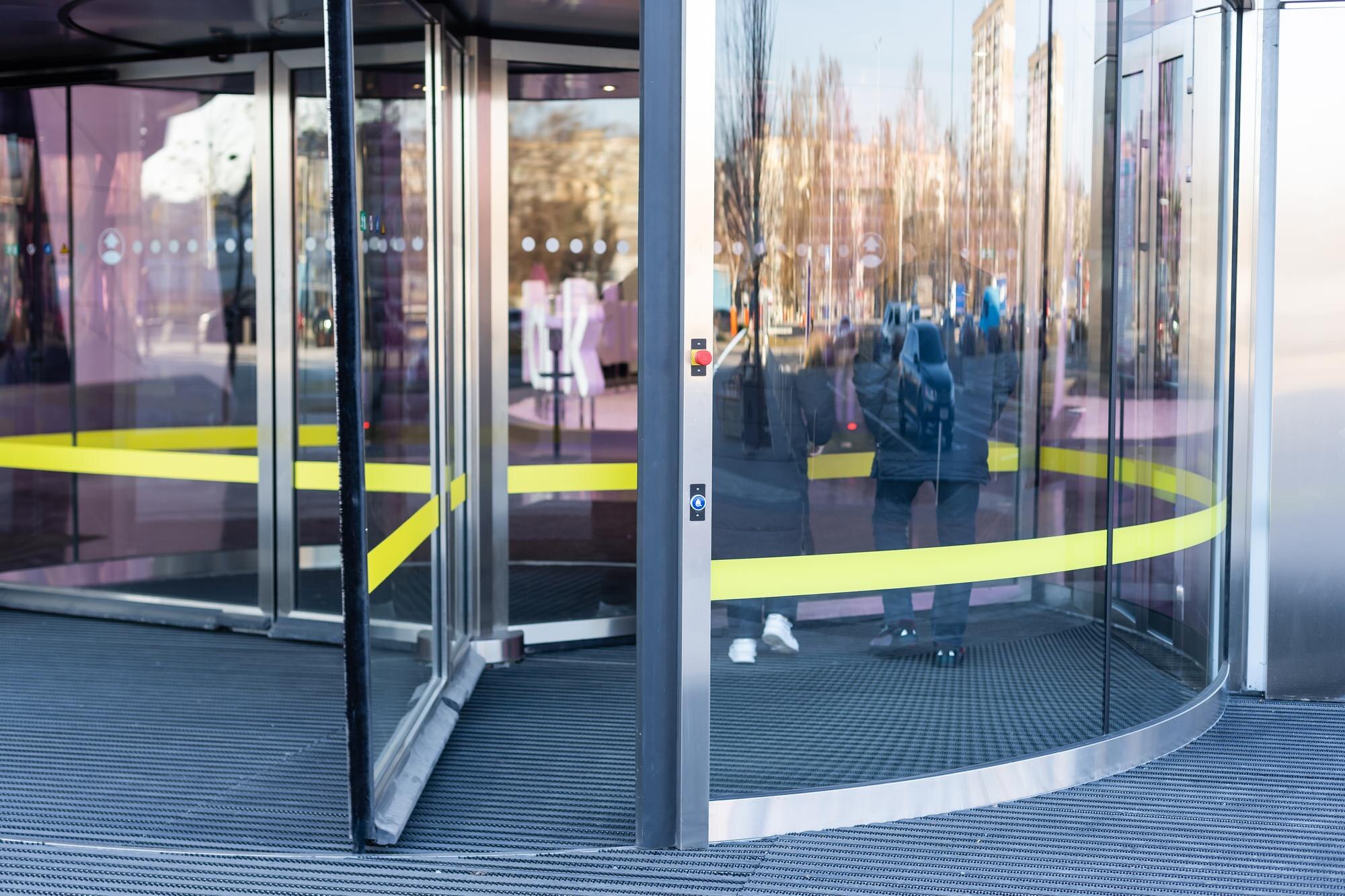 Portes tournantes automatiques en verre installées à l’entrée d’un bâtiment moderne.